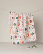 Mahjong tile print tea towel in pink green orange on cream background hanging on cord