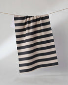 Black and beige horizontal striped tea towel hanging on a rope clothesline