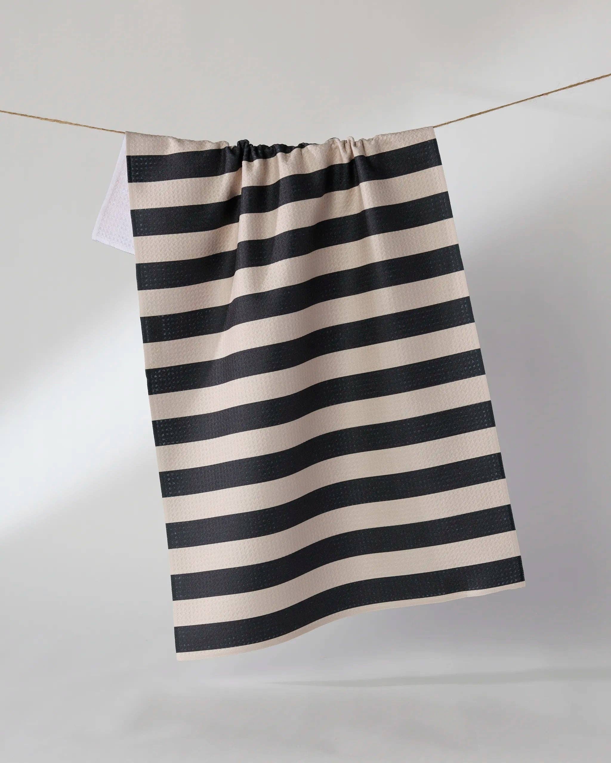 Black and beige horizontal striped tea towel hanging on a rope clothesline
