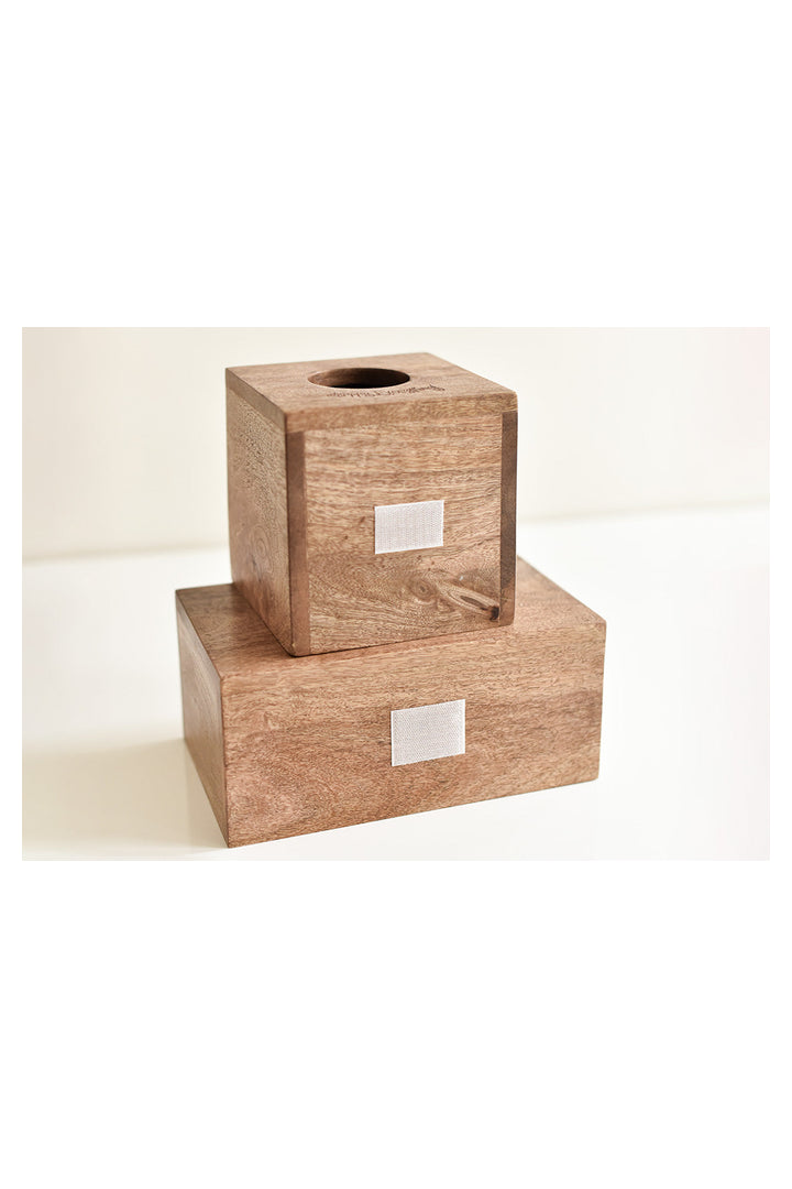 Two stacked natural wood tissue box covers with white velcro label patches on cream background
