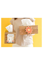Two wooden tissue boxes with decorative stickers held by a person against yellow background