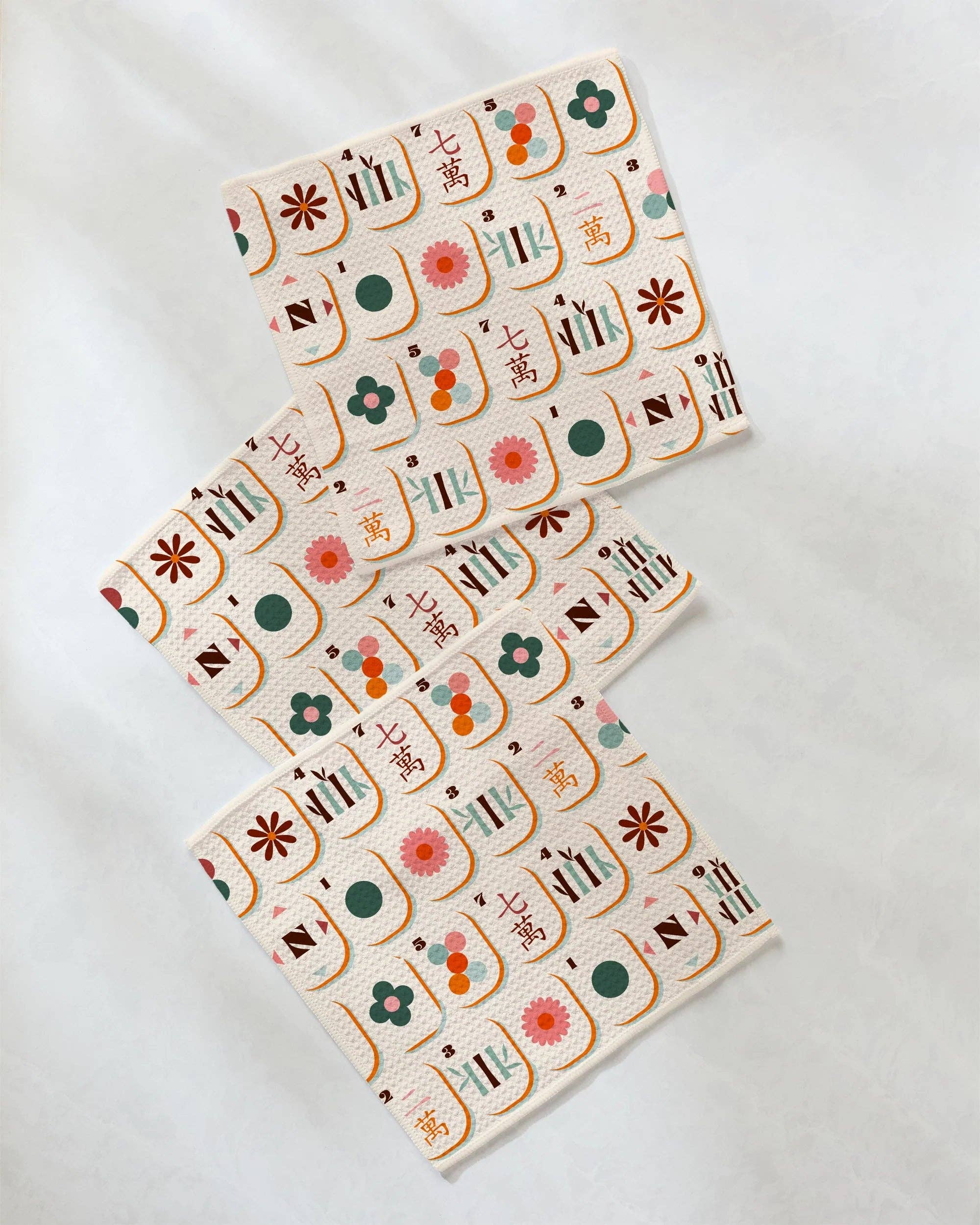Set of three mahjong-print dishcloths with colorful floral and tile pattern on cream background