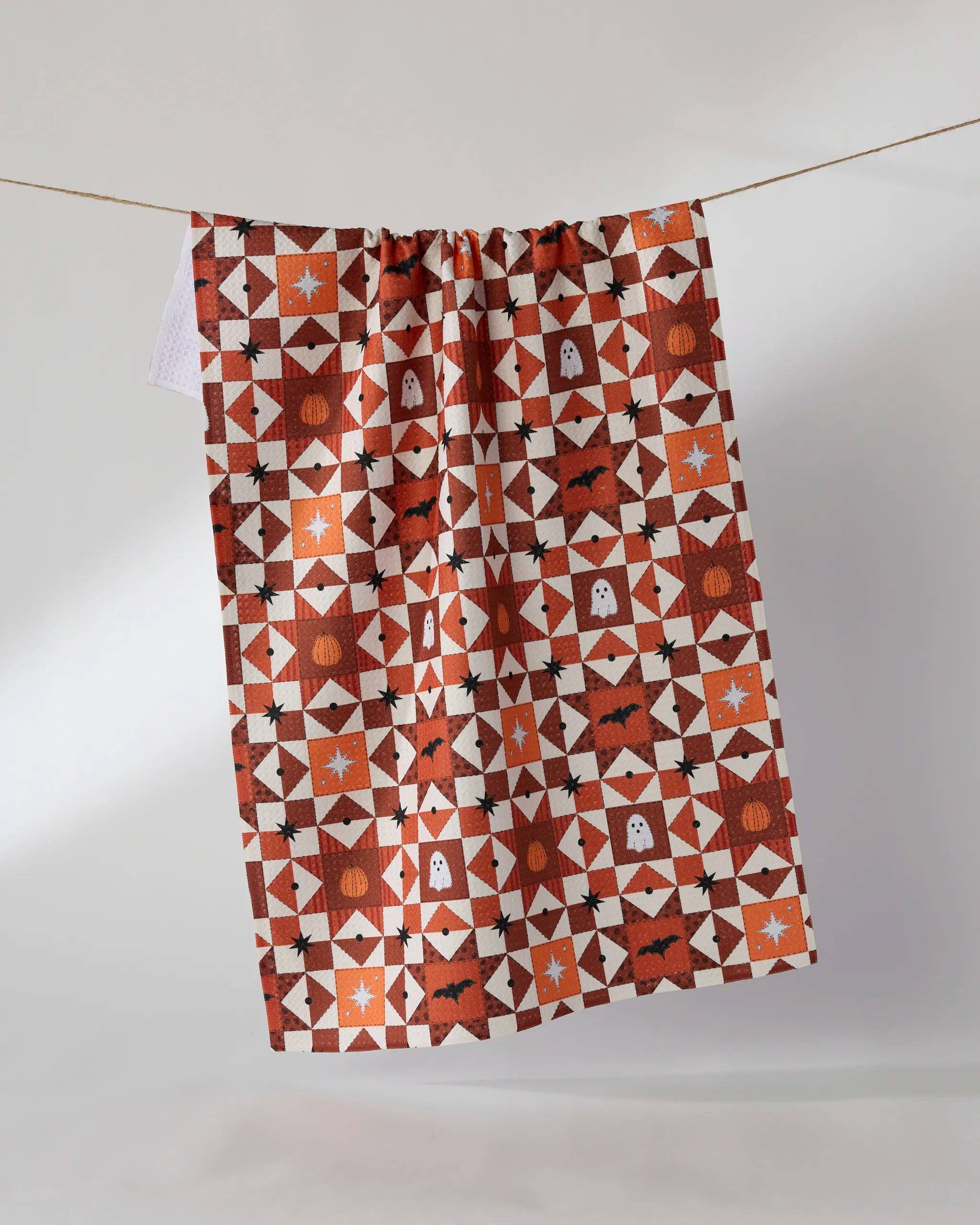 Halloween tea towel with orange geometric quilt pattern featuring ghosts, bats, pumpkins, stars